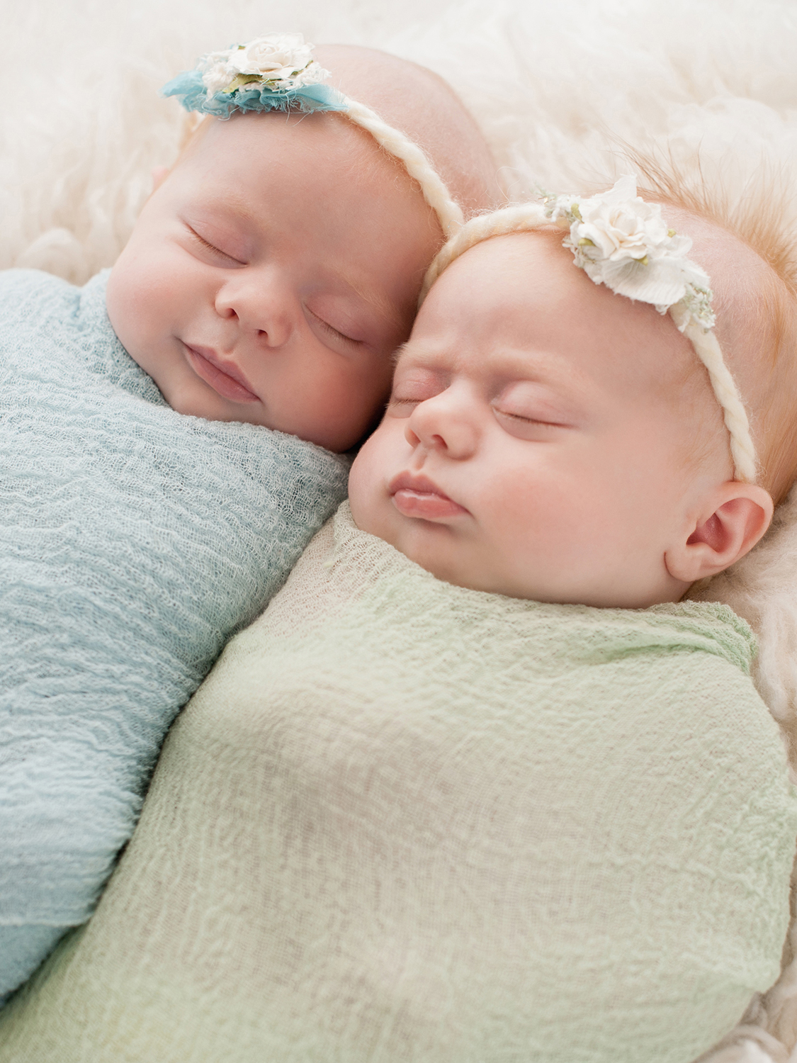 Twin babies in a blue & green swaddle